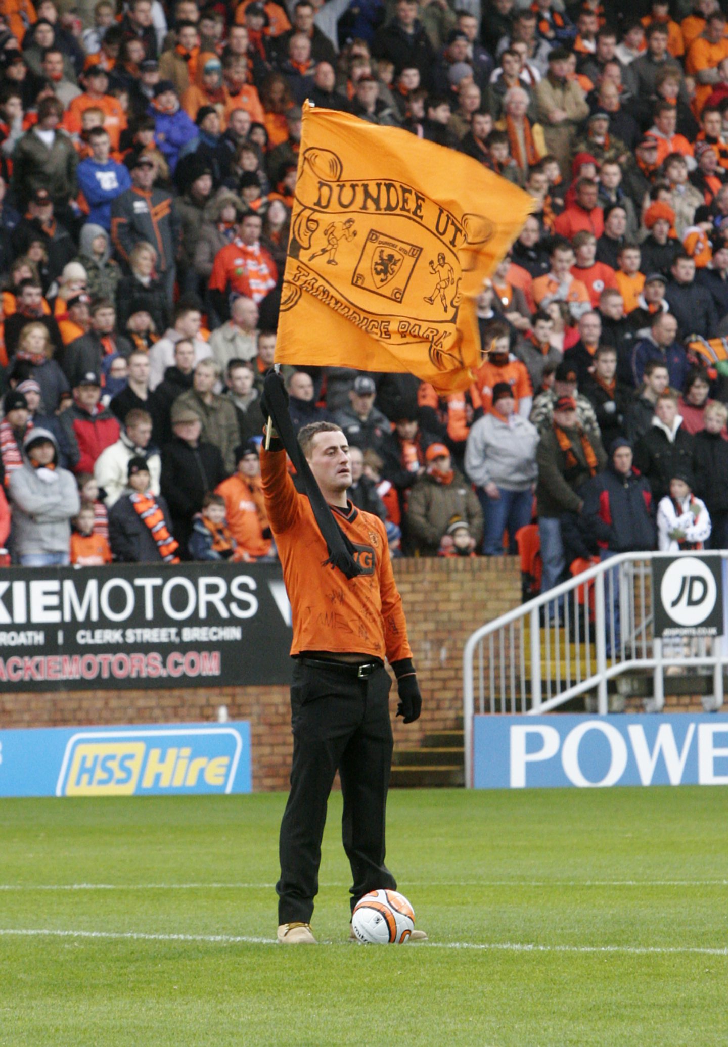 United fan Keith Whelan holds the club's flag aloft on the pitch at Tannadice. Image: DC Thomson.