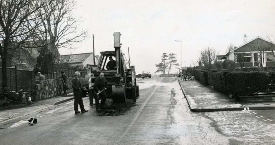 Workmen dig up the surface of the road. Image: DC Thomson.