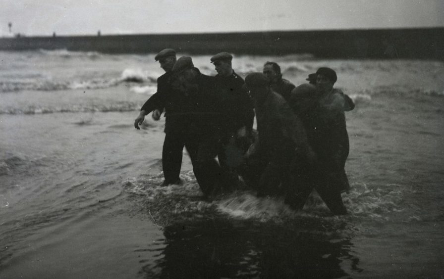 Rescuers bring a body ashore at Arbroath beach following the loss of the Robert Lindsay. Image: DC Thomson.