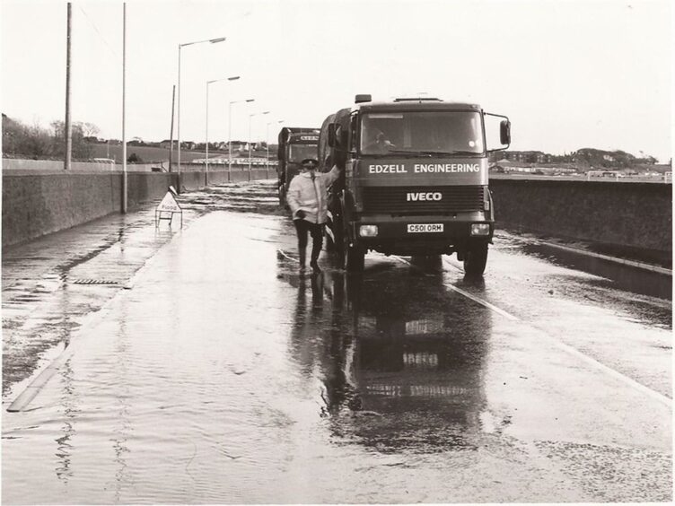 Sergeant Sandy Smith hitches a lift on an Edzell Engineering Iveco lorry to get through the flooded Dundee Road, Arbroath, in January 1993.