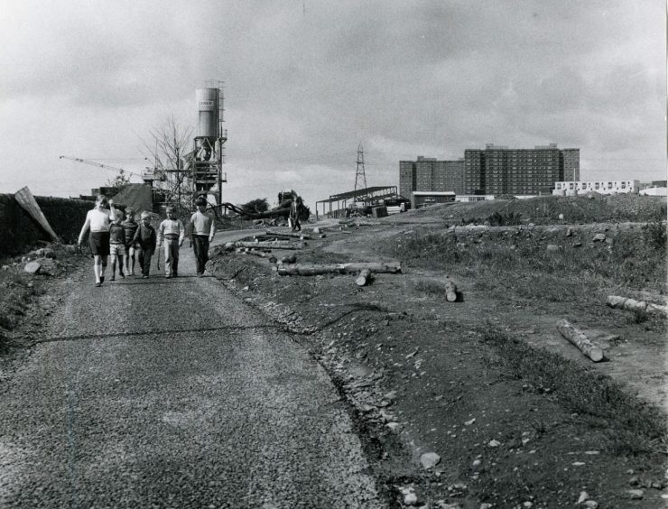 Young children walking down an empty path with the multi-storey blocks in the background. Image: DC Thomson.