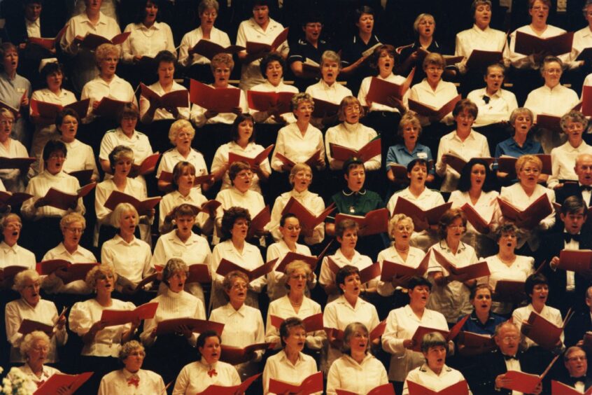A large group of carol singers performs in the Caird Hall, Dundee