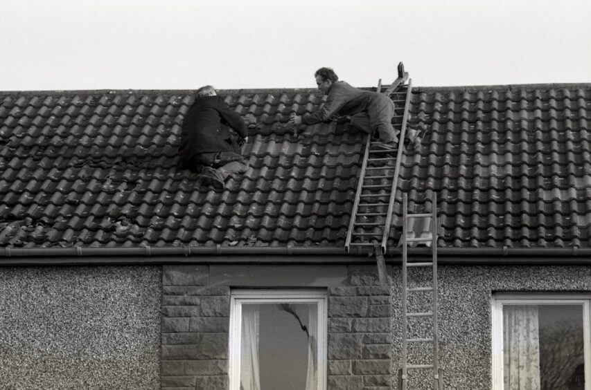 Locals patching up a stricken roof after the Lockerbie bombing