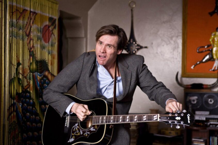 Jim Carrey playing the guitar as Carl in a scene from the 2008 movie. 