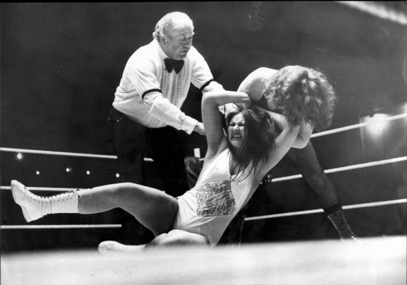Cherokee Princess Gloria Young and Rusty Blair do battle in the ring as the referee looks on...