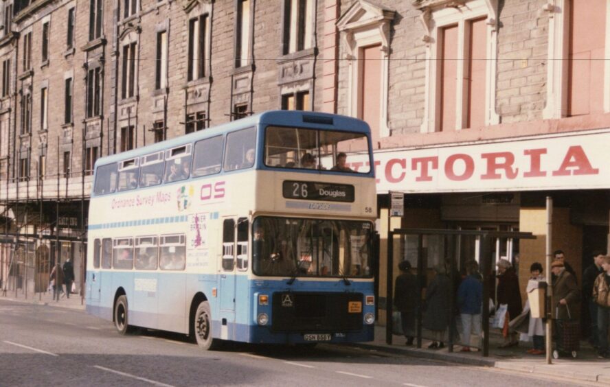 People queue at the bus stop as Bus 58, in the updated Tayside Buses livery, picks up outside the Victoria cinema in 1986.