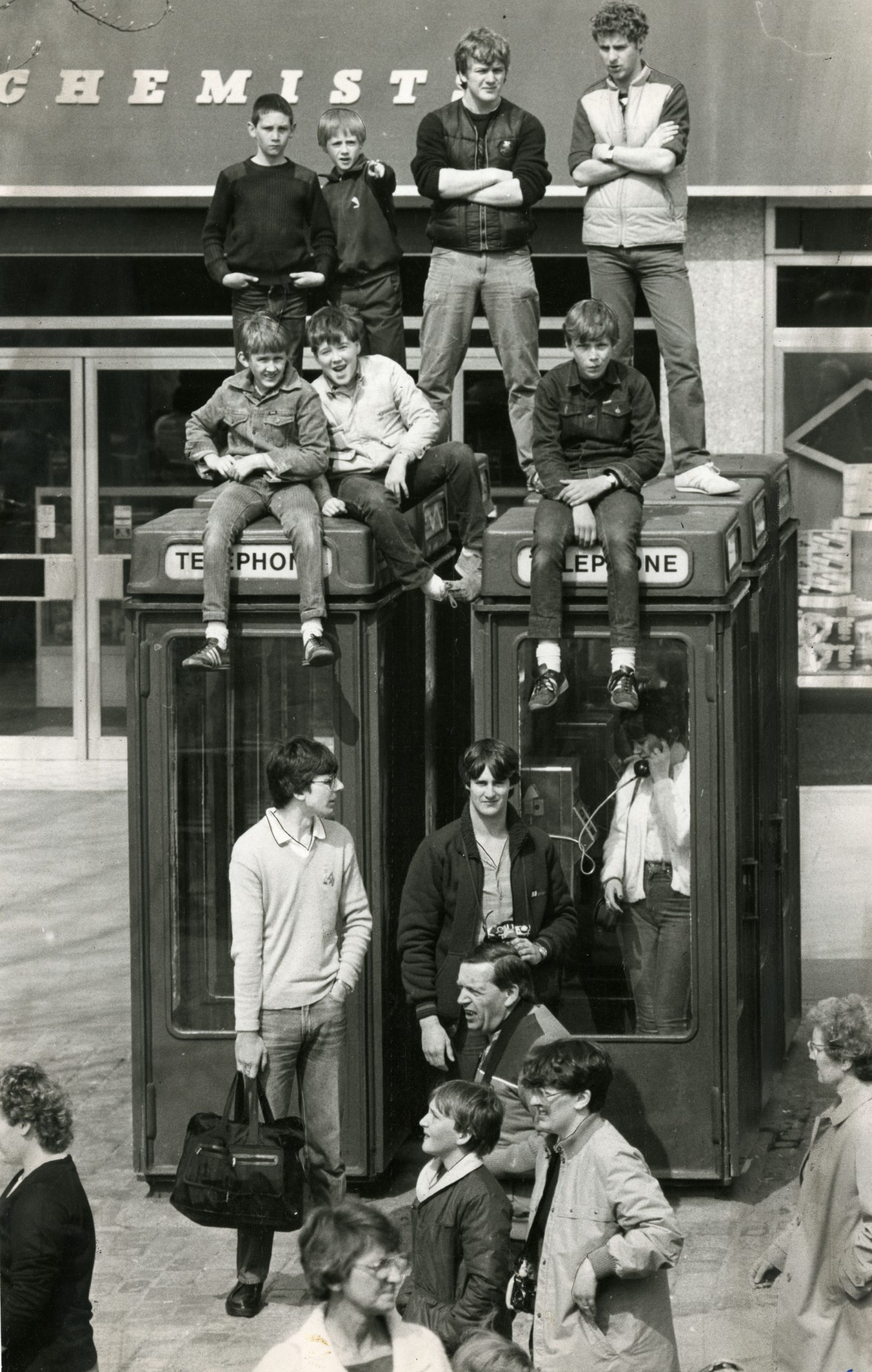 Boys watch the marathon from atop telephone kiosks
