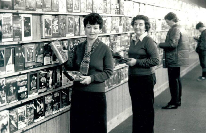 People browse the walls of VHS tapes at Magic Eye in the Keiller Centre, Dundee, in 1982