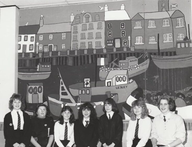 Pupils standing before the fishing mural. 