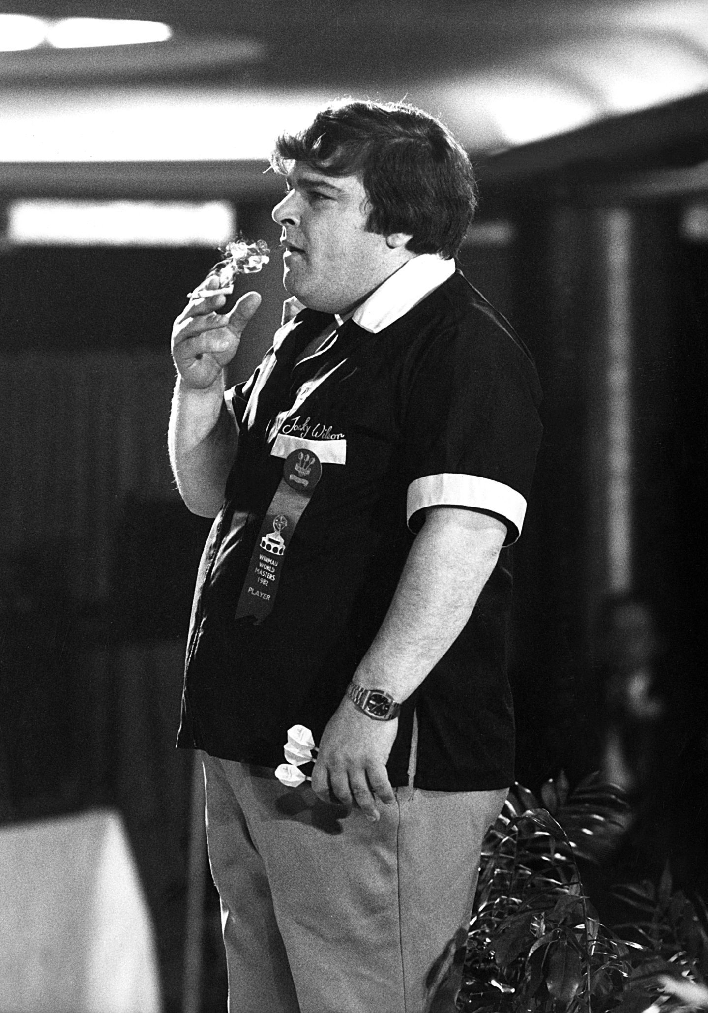 Jocky Wilson smokes a cigarette on stage during the 1982 Winmau World Masters. Image: Shutterstock.
