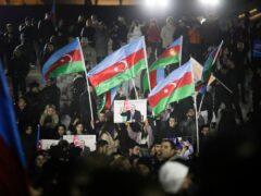 People wave national flags celebrating Azerbaijan’s President Ilhan Aliyev’s victory in the presidential election in Baku, Azerbaijan (AP)