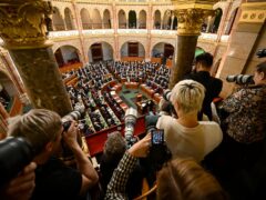 Photographers take pictures as Hungarian prime minister Viktor Orban, centre right, stands at a parliament session (AP Photo/Denes Erdos)