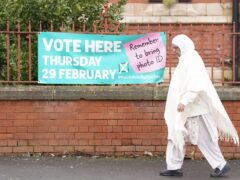 A woman walks past a sign for a polling station location in Rochdale, Greater Manchester (Danny Lawson/PA)