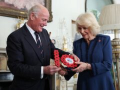 President of the Poppy Factory Surgeon Rear Admiral Lionel Jarvis hands a gift to Queen Camilla during a celebration at Clarence House (Isabel Infantes/PA)