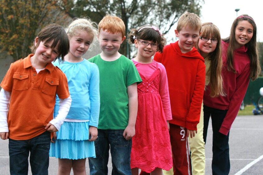 The pupils line up in the playground in rainbow colours.