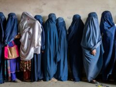 Afghan women wait to receive food rations distributed by a humanitarian aid group, in Kabul (Ebrahim Noroozi/AP)