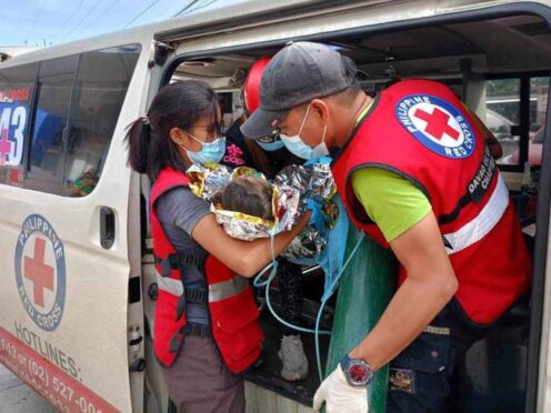 Rescuers provide medical attention to a child after the landslide (Philippine Red Cross via AP)