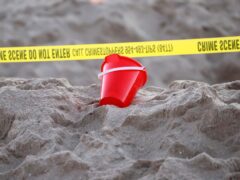 A bucket rests next to caution tape on a beach in Lauderdale-by-the-Sea, Florida (Mike Stocker/South Florida Sun-Sentinel via AP)