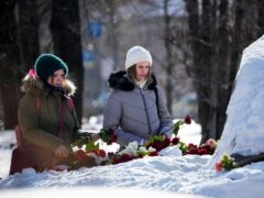 Young women lay flowers to pay the last respect to Alexei Navalny at the monument, a large boulder from the Solovetsky islands, where the first camp of the Gulag political prison system was established, near the historical the Federal Security Service (FSB, Soviet KGB successor) building in Moscow, Russia (Alexander Zemlianichenko/AP)