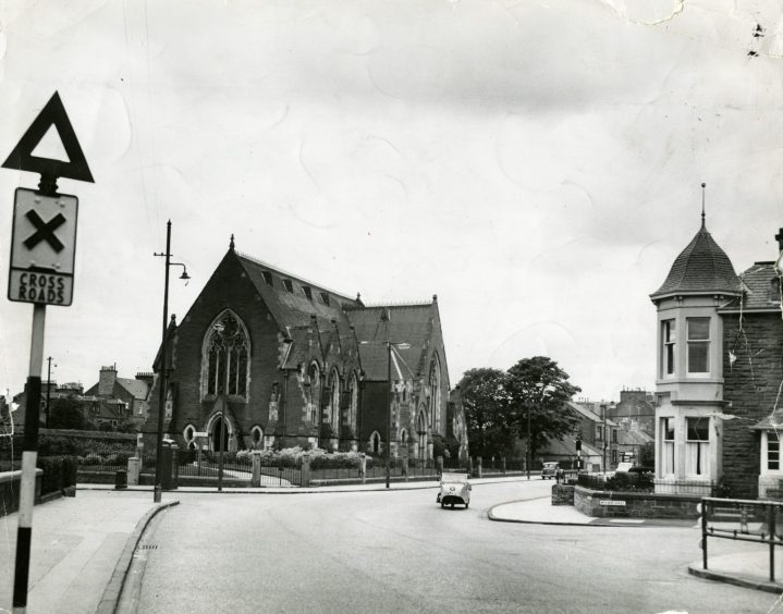 The crossroads at the junction of Queen Street and Monifieth Road in 1957, with a church in the background