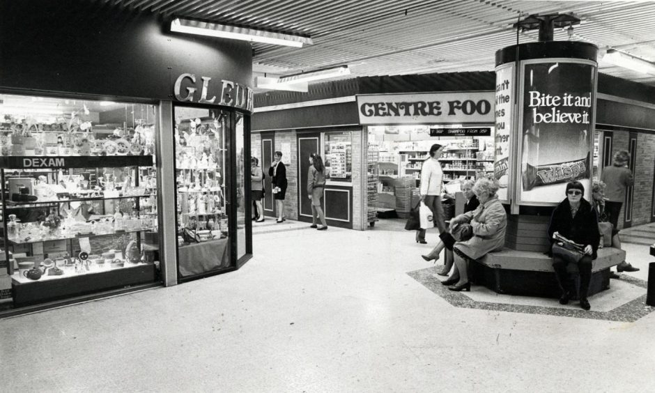 People sit on a bench outside some of the centre's shops