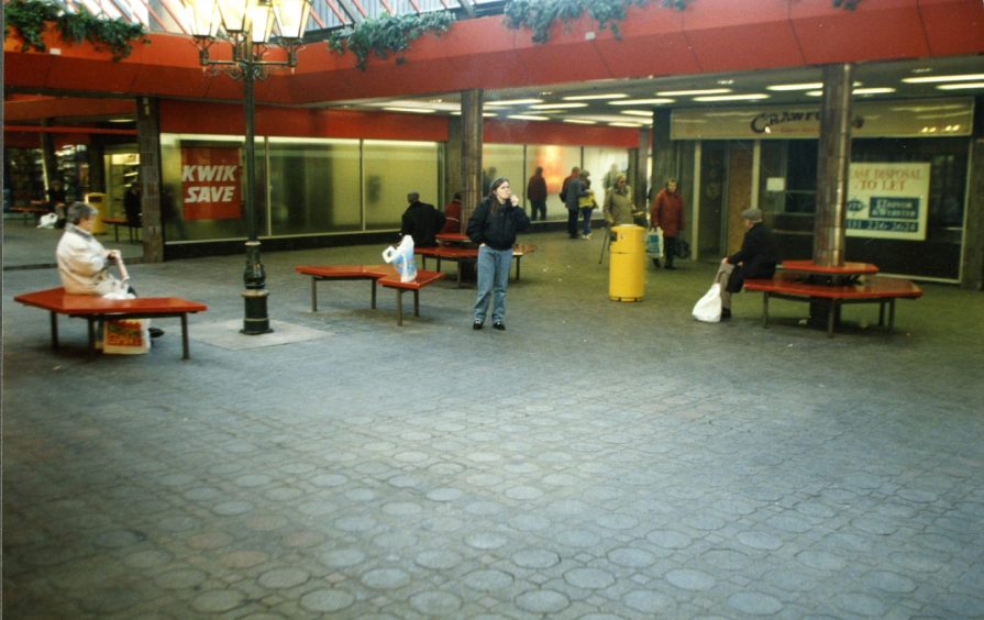 People sit on benches outside the Highgate Shopping Centre.