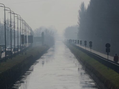 A man walks along the Naviglio Pavese canal shrouded in mist and smog in Milan, Italy (Luca Bruno/AP)