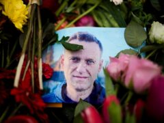 Raindrops cover a portrait of Russian opposition leader Alexei Navalny, placed between flowers in front of the Russian embassy in Berlin (Markus Schreiber/AP)