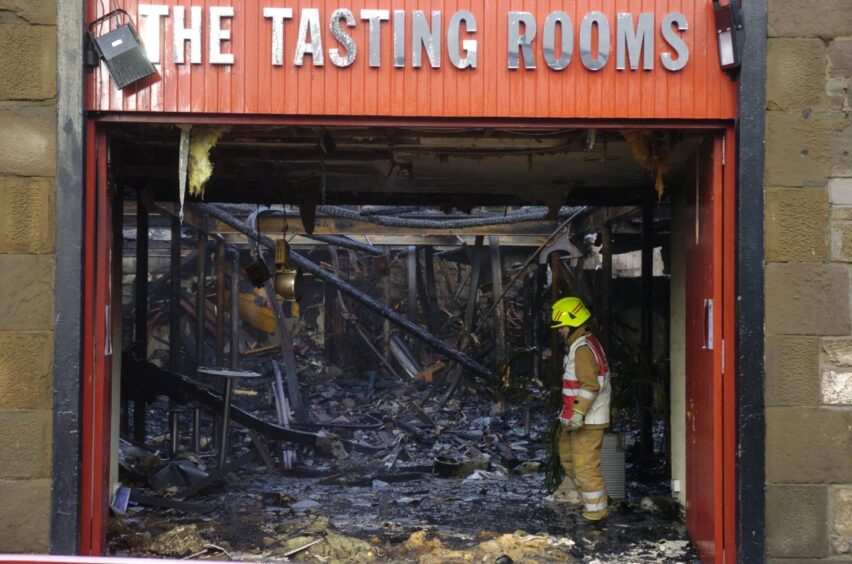 A firefighter stands amid the charred interior of the Dundee building after The Tasting Rooms were destroyed by fire. 