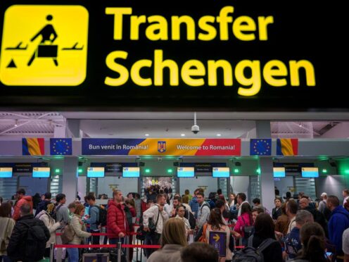 Passengers arriving at Henri Coanda International Airport in Romania pass under a Schengen Information sign (Andreea Alexandru/AP)