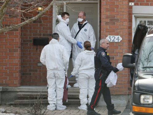 Members of the coroner’s office stand outside the house where the murders occurred (Patrick Doyle/The Canadian Press via AP)