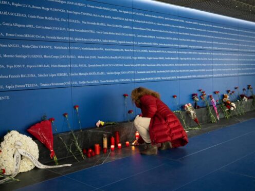A woman lights a candle at a memorial for the train bombing victims in Madrid, Spain (Bernat Armangue/AP)