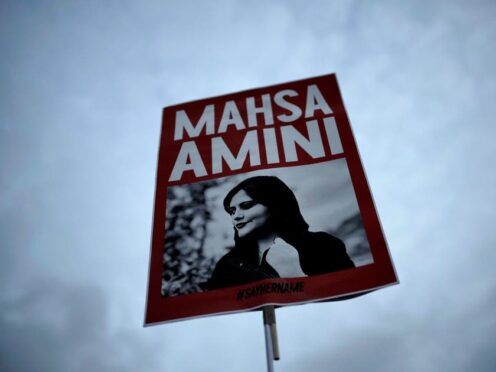 A woman holds a placard with a picture of Iranian woman Mahsa Amini (Markus Schreiber/AP)