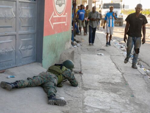 Pedestrians walk past a soldier guarding the area near the international airport in Port-au-Prince, Haiti (Odelyn Joseph/AP)