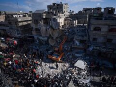 Palestinians search for bodies and survivors in the rubble of a residential building destroyed in an Israeli air strike in Rafah (AP)