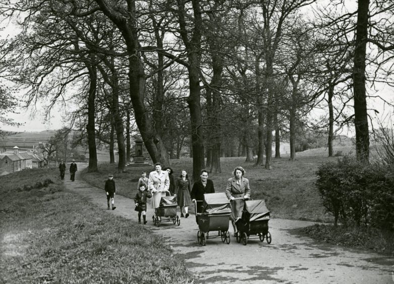 Families, including mums pushing prams, out for a stroll in 1947. 