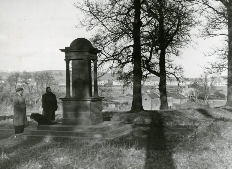 Two people and a dog beside the drinking fountain that was erected in 1922. 