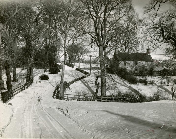 A house, path and fields covered in snow in Den O' Mains in 1953