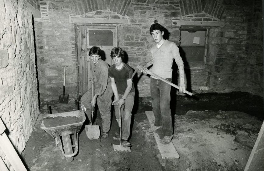 Three young workers clearing out rubble from one of the lower areas in Mains Castle