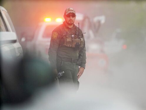 A US customs and border agent disappears into the dust as investigators drive to the site of the crash (Joel Martinez/The Monitor via AP)