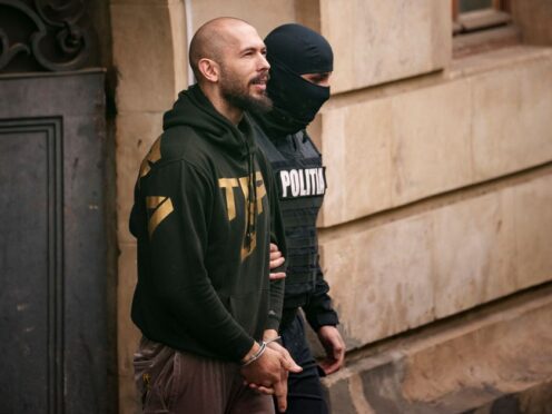 A police officer escorts Andrew Tate from the Court of Appeal in Bucharest (AP Photo/Andreea Alexandru)
