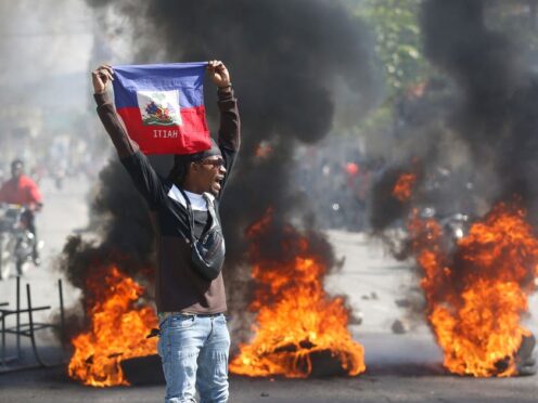 A demonstrator holds up an Haitian flag during protests (Odelyn Joseph/AP)