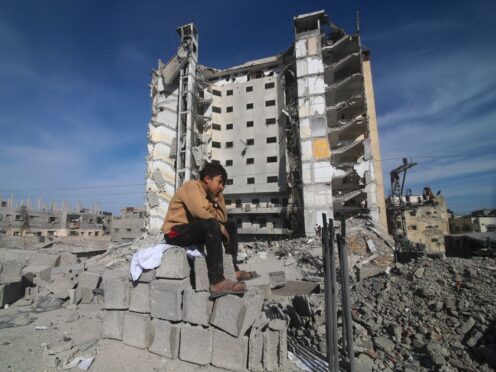A Palestinian boy sits outside a residential building destroyed in an Israeli strike in Rafah, Gaza Strip (Hatem Ali/AP)