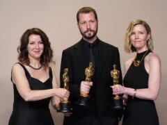 Raney Aronson-Rath, Mstyslav Chernov, and Michelle Mizner after they won the award for best documentary feature film for 20 Days In Mariupol. (Jordan Strauss/Invision/AP)