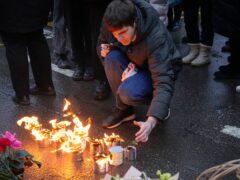 A man lights candles at the fence next to the Crocus City Hall in Moscow (Alexander Zemlianichenko/AP/PA)