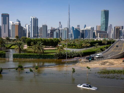 An abandoned vehicle stands in floodwater caused by heavy rain with the Burj Khalifa in the background (AP)