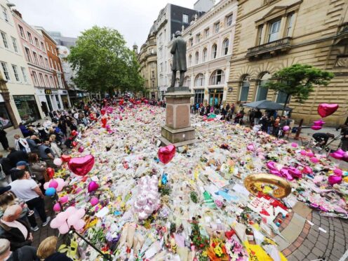 People look at flowers and tributes left in St Ann’s Square in Manchester after the attack in 2017 (Owen Humphreys/PA)