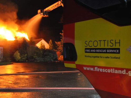 Handout photo issued by SFRS of one of its vehicles as a fire rages in the background (SFRS/PA)
