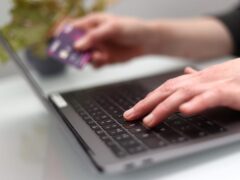 A woman using a laptop as she holds a bank card (PA)