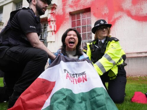 Police officers detain a person after members of Youth Demand threw red paint over the outside of the Ministry of Defence building in London (Lucy North/PA)